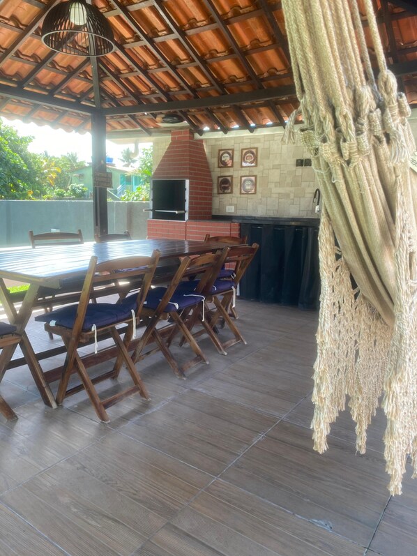 An outdoor patio with a brick oven, wooden table and chairs, and macrame hanging. - Solar dos Oliverias Serrambi by La Playa (Ipojuca)