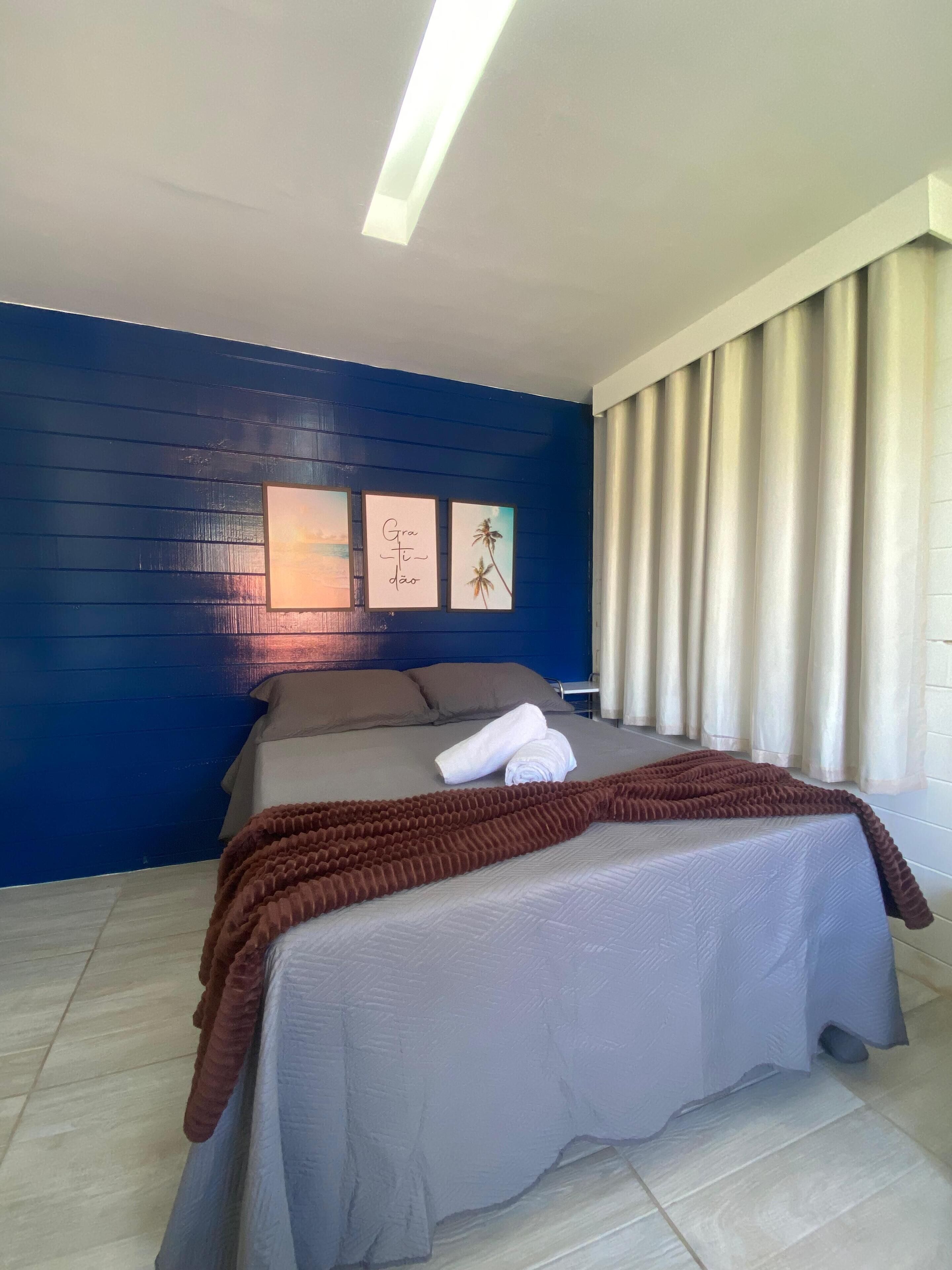Une chambre d’hôtel avec un lit, un plaid marron et un mur orné de trois tableaux.