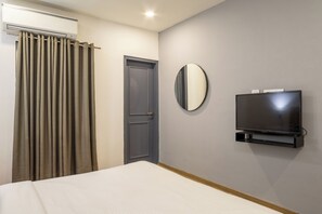 A hotel room with a bed, a television mounted on the wall, a door, and a curtain. - Housr Sector 57 Gurgaon Near Golf Course Extension (Gurugram)