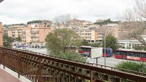 Un balcon donnant sur une rue de la ville, avec vue sur les voitures et les autobus garés.