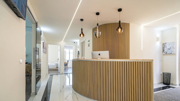 A modern reception desk with a curved design, a laptop on top, and pendant lighting. - Rooms & Breakfast Centrale (Fabriano)