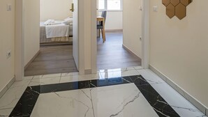 A hallway with a black and white marble floor, a hexagonal wall decoration, and a bed in the background. - Rooms & Breakfast Centrale (Fabriano)