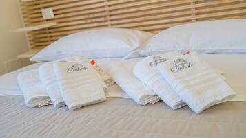 A neatly made bed with white linens and towels, a wooden headboard, and white pillows.