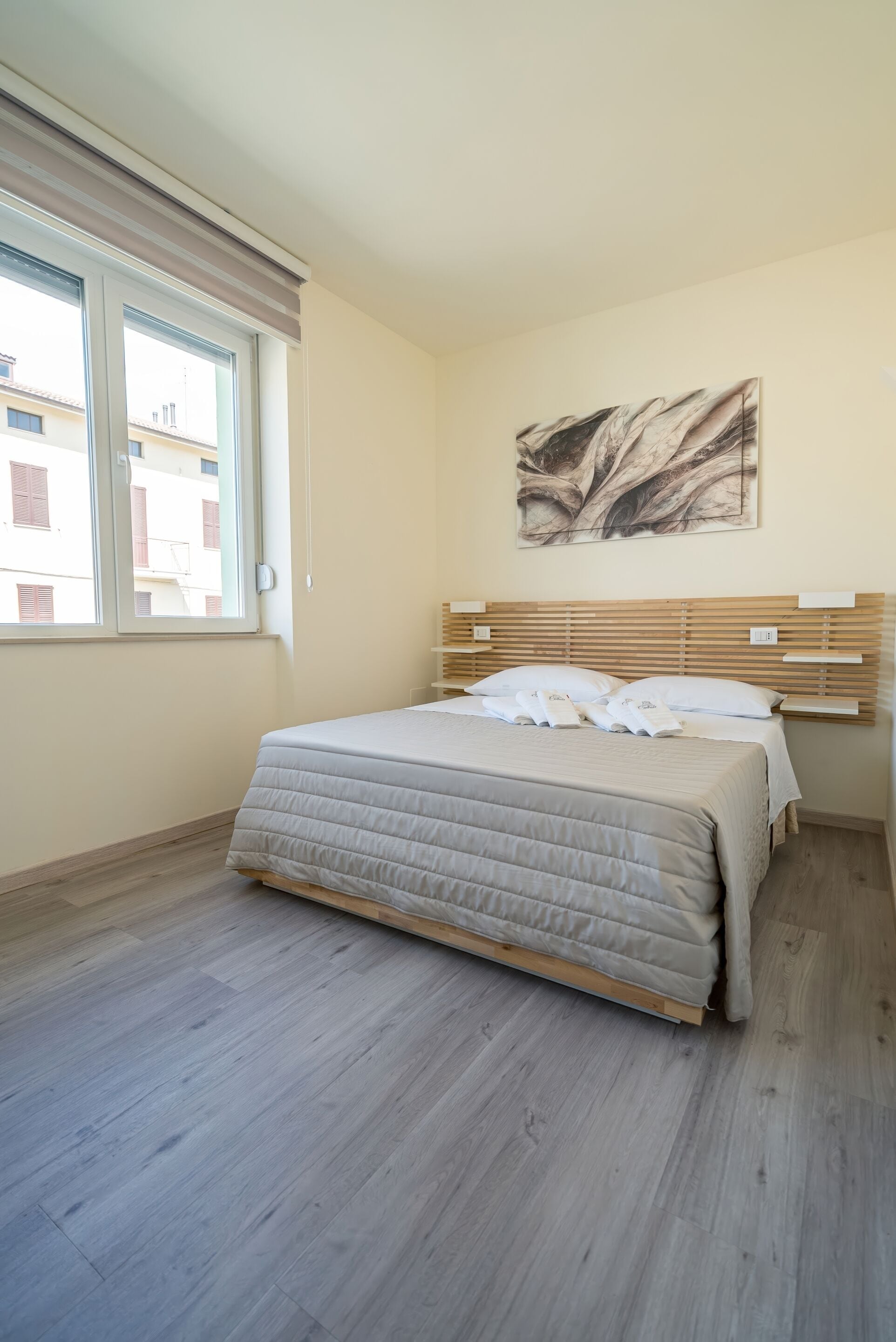 Una camera da letto con un letto, una finestra e un'opera d'arte appesa al muro.