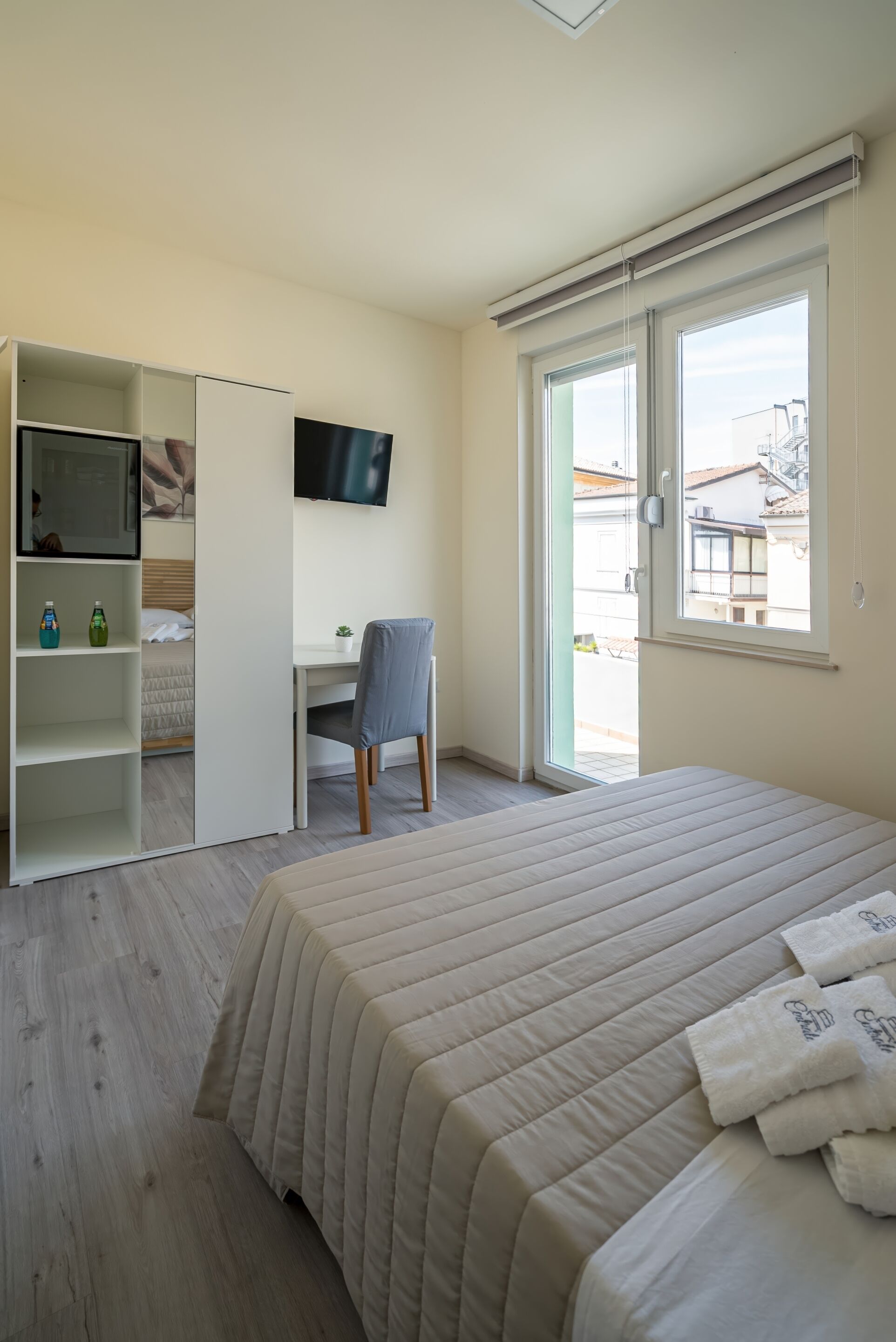 A bedroom with a bed, a desk, a chair, a TV, and a wardrobe.