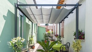 Un espacio cubierto con una mesa y sillas, rodeado de plantas en macetas.