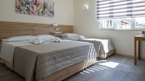A bedroom with two beds, a wooden headboard, a window with blinds, and a painting on the wall. - Rooms & Breakfast Centrale (Fabriano)