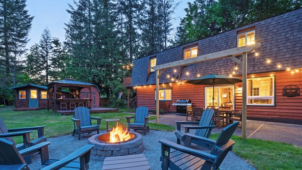 A wooden cabin with a fire pit and outdoor seating. - Cozy River Cabin - Sleeps 12 - Hot Tub - EV - Trails & Stevens Pass Nearby (Gold Bar)