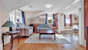 A spacious living room with a wooden floor, two sofas, a coffee table, and a fireplace.