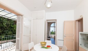 Enjoy a meal at the round dining table with a bowl of fresh vegetables and a glass cabinet nearby.