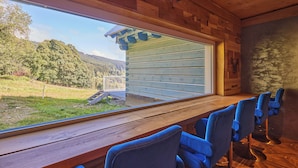 Ein Holzinnenraum mit einem großen Fenster mit Blick auf ein bewaldetes Gebiet.