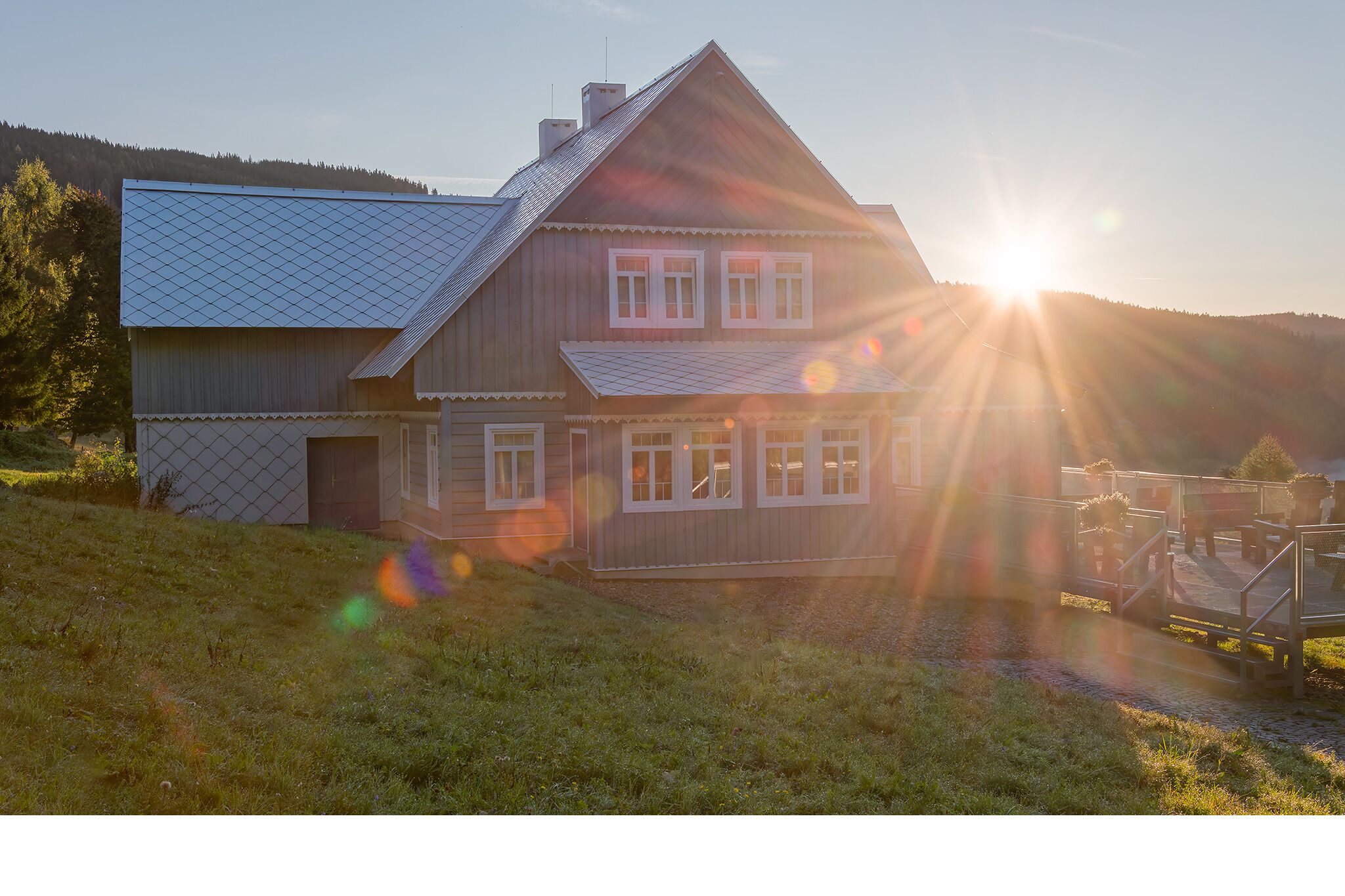 A two-story house with a sloped roof, a visible garage, and a small deck area.