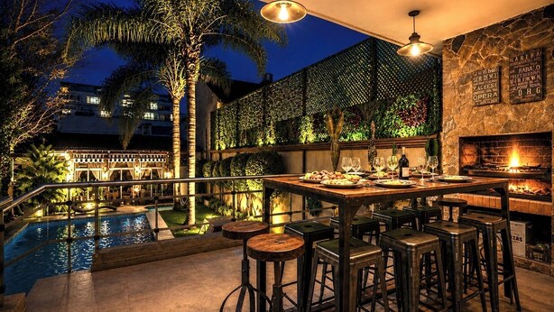 Un bar en la azotea con piscina, taburetes de bar y una chimenea de piedra.