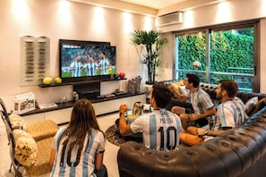Una sala de estar con televisor, sofá y mesa de centro.
