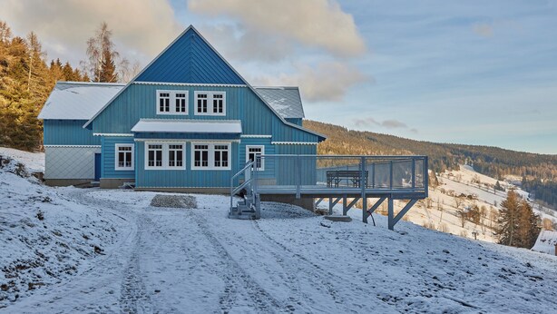 Een blauw huis met een trap naar een terras.