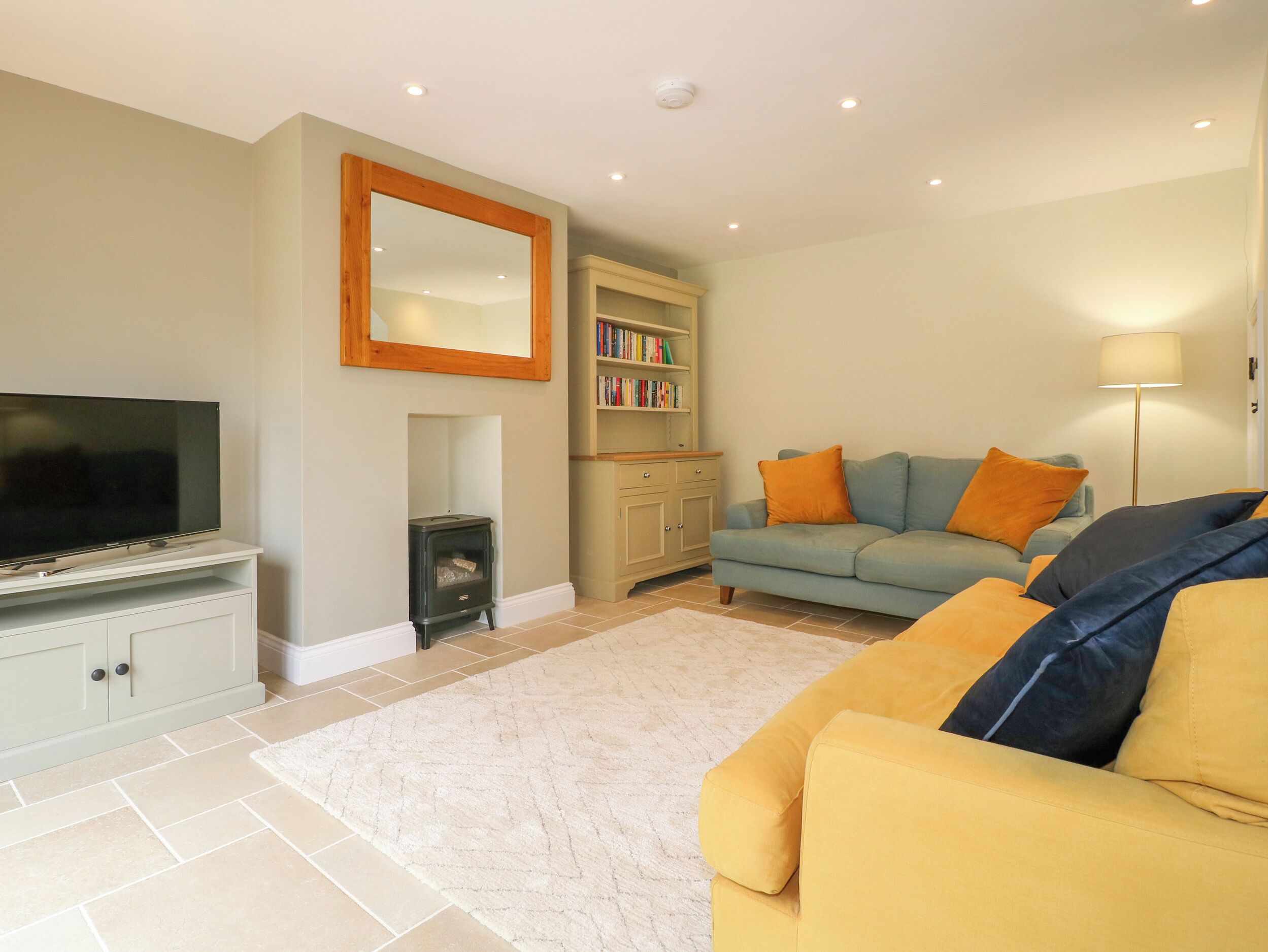 A living room with a television, a fireplace, a sofa, and a bookshelf.