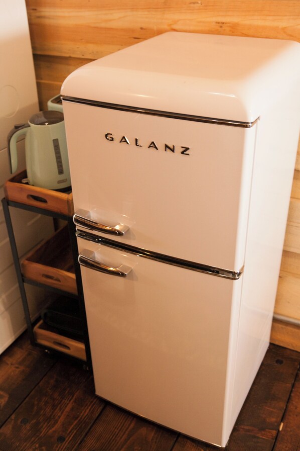 A white Galanz refrigerator with a chrome handle and a wooden cabinet below it.