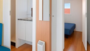A compact room with a kitchenette, a bed, and a small window. - Coastal Bloom Pool & Garden Stay  (Conil de la Frontera)