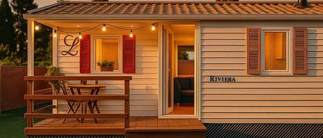 A single-story building with a covered patio, a dining area with a table and chairs, and a nameplate reading "RIVIERA".