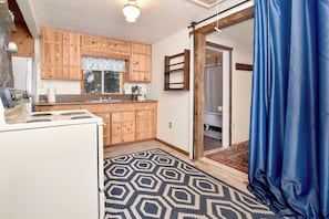 A compact kitchen with wooden cabinets, a white stove, and a patterned rug.