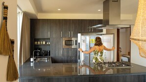 Une cuisine moderne avec des meubles en bois foncé, des appareils électroménagers en acier inoxydable et un îlot central.