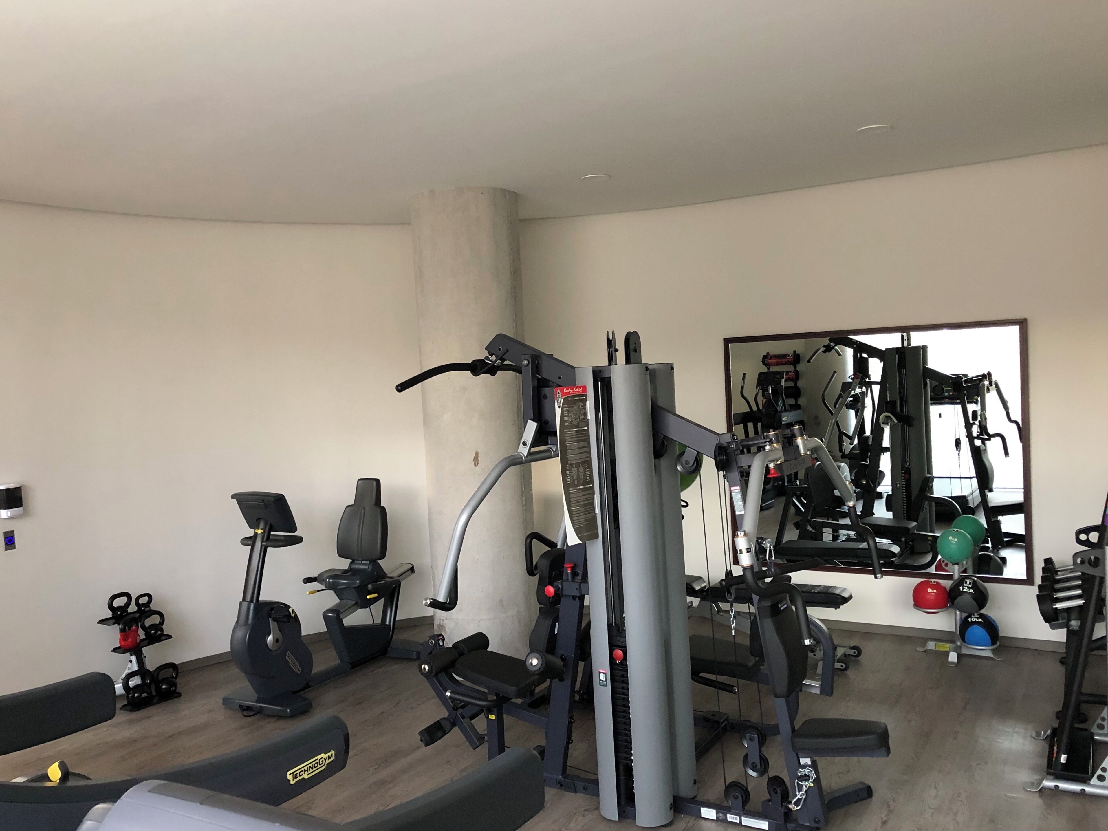Un gimnasio con diverso equipo de ejercicio, que incluye cintas de correr, máquinas de pesas y pesas libres.