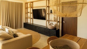 Una sala de estar moderna con un sofá, una mesa de comedor de madera, un televisor montado en la pared y una cesta decorativa.