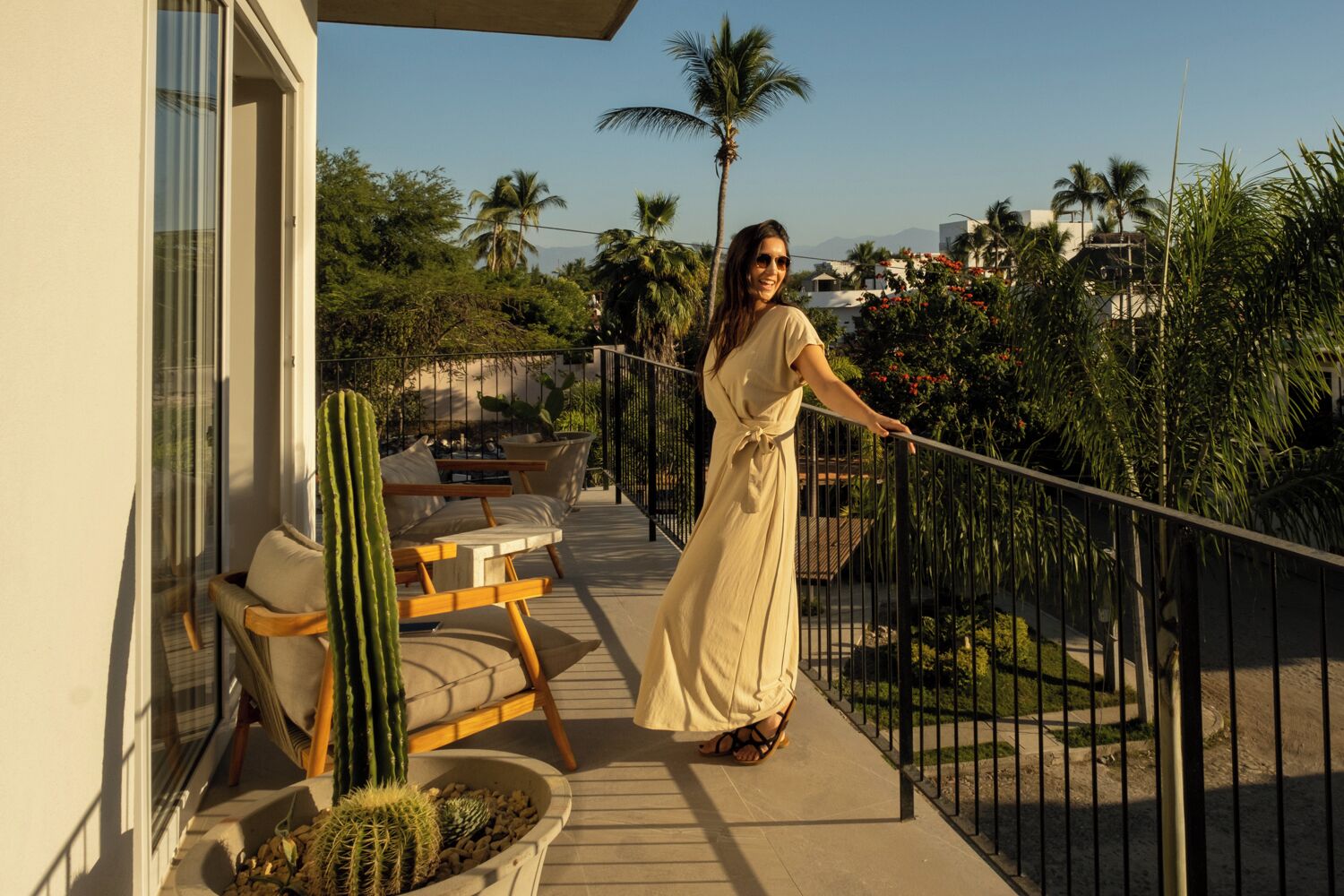 A balcony with a seating area, a cactus, and a railing.