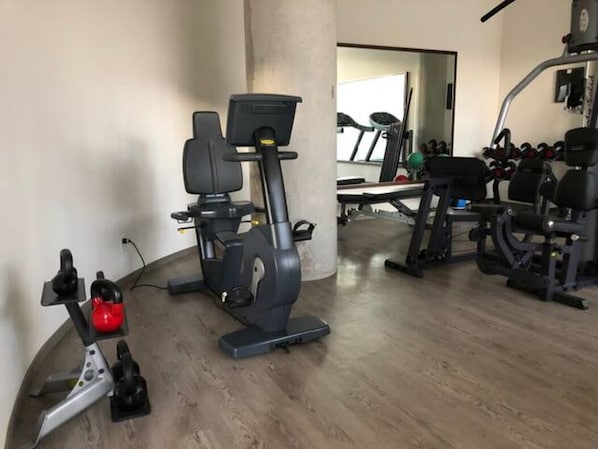 Et hjemmegymnasium med motionscykel, løbebånd og forskelligt træningsudstyr.