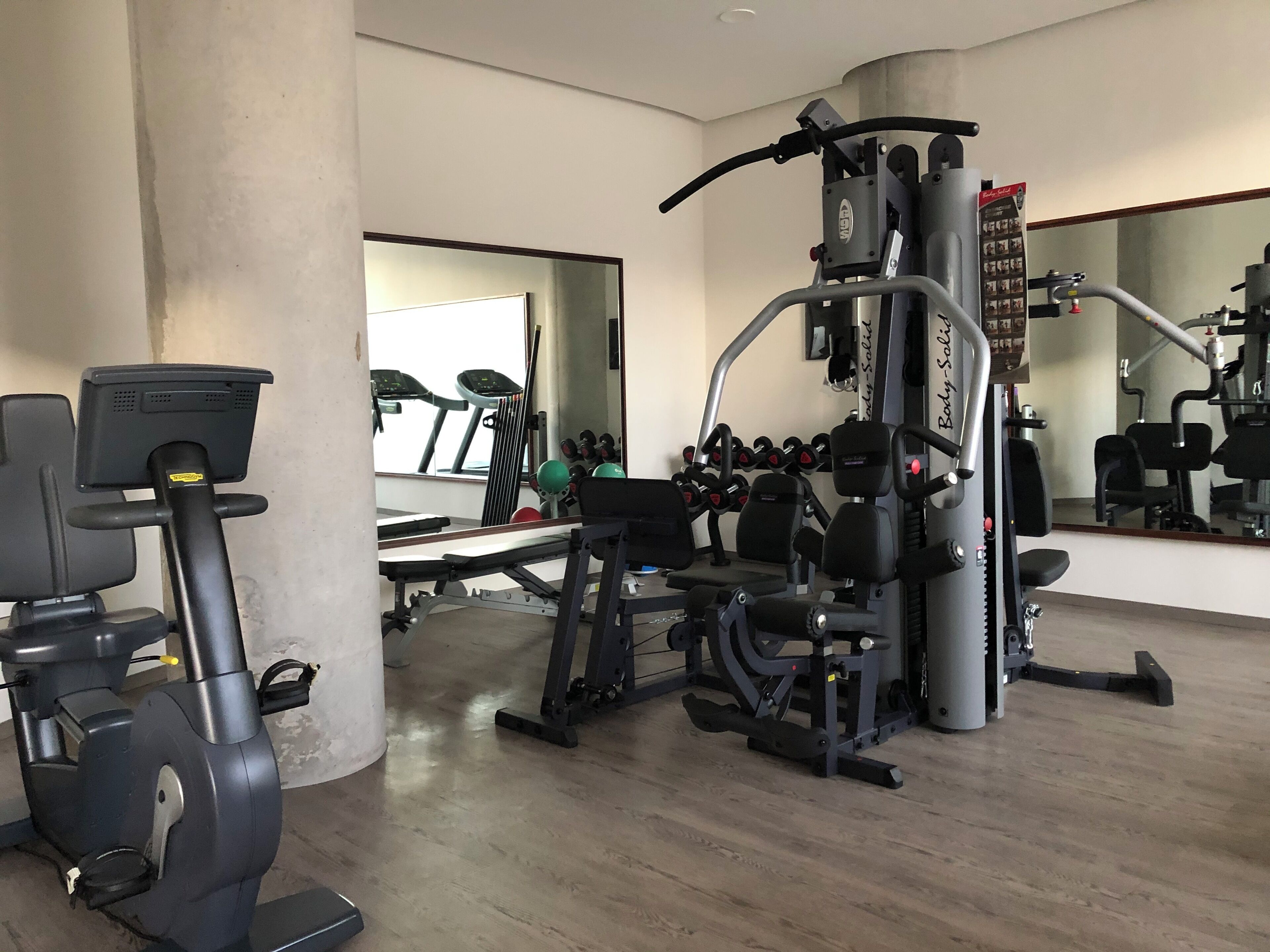 Ein Fitnessstudio mit Cardiogeräten, Krafttrainingsgeräten und Kurzhanteln.