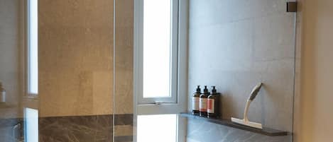 Une salle de bain moderne avec une douche à parois de verre, des toilettes et une petite fenêtre.