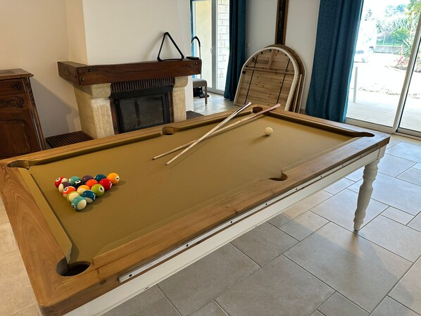 A pool table with balls and cues, a fireplace, and a view through a glass door. - Villa Chantebise - Elegance and calm with private pool (Tresques)