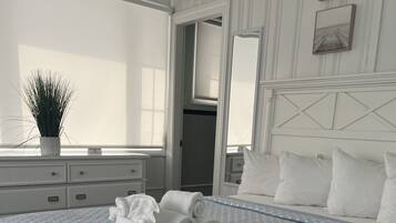 A neatly made bed with rolled towels, a potted plant, and a large window in a hotel room.