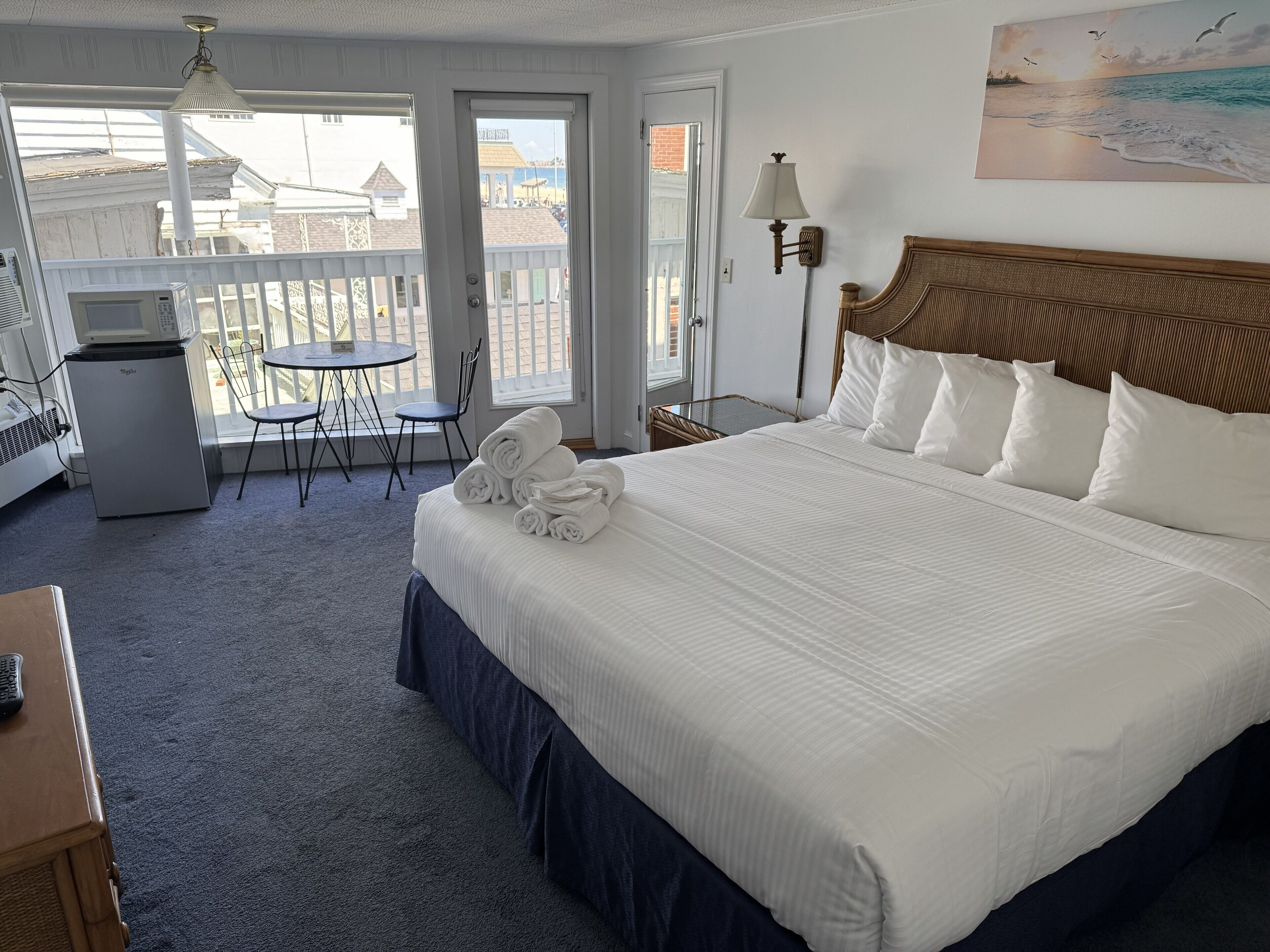 Une chambre d’hôtel avec un grand lit, un bureau avec un ordinateur, une chaise, un balcon avec vue et un tableau au mur.