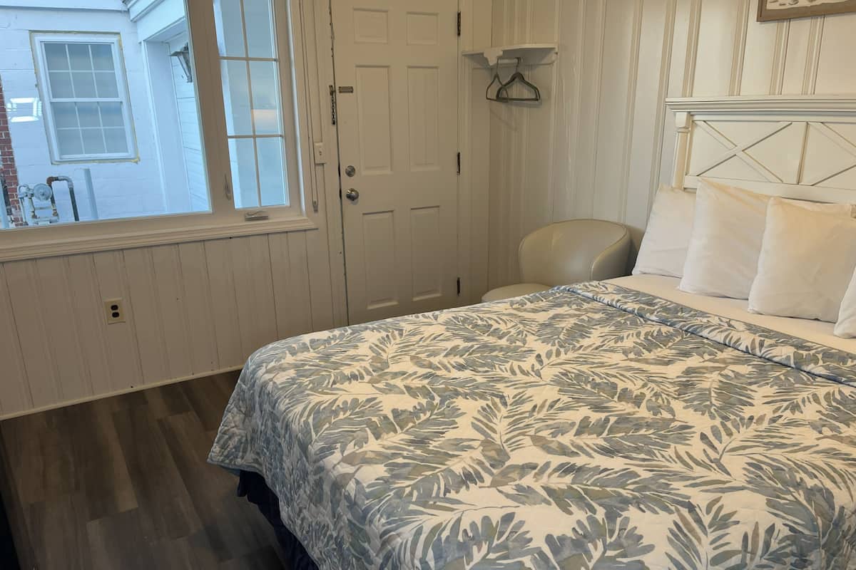A bedroom with a bed, a chair, a window, and a door.