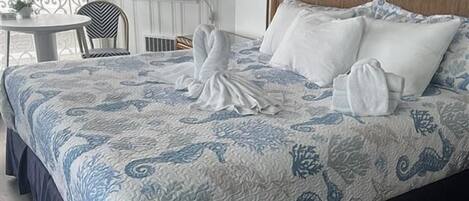 A hotel room with a large bed, a round table, and a chair.