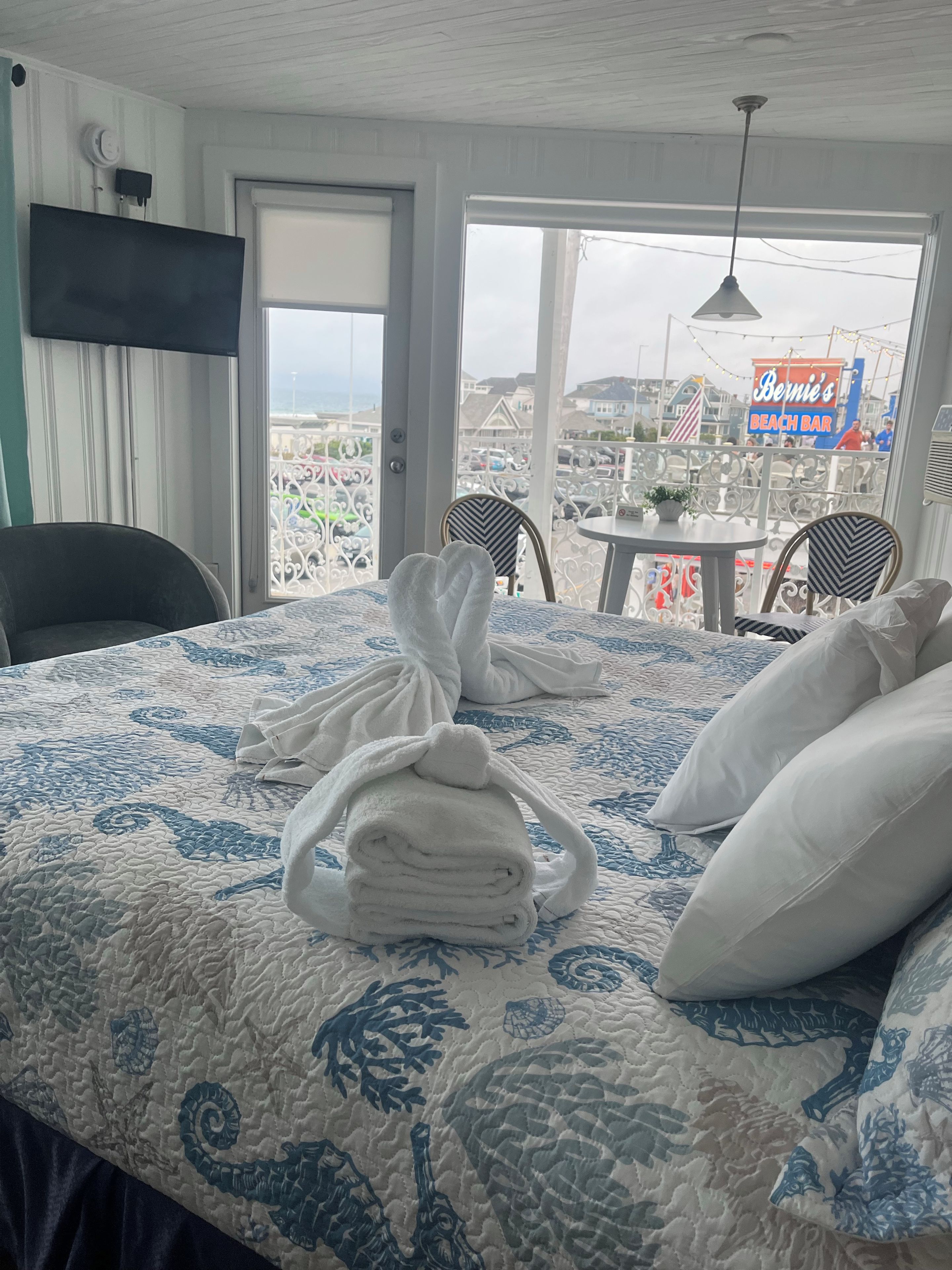 Habitación de hotel con cama, una silla, una mesa y vistas al bar de la playa.