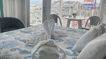 Habitación de hotel con cama, una silla, una mesa y vistas al bar de la playa.