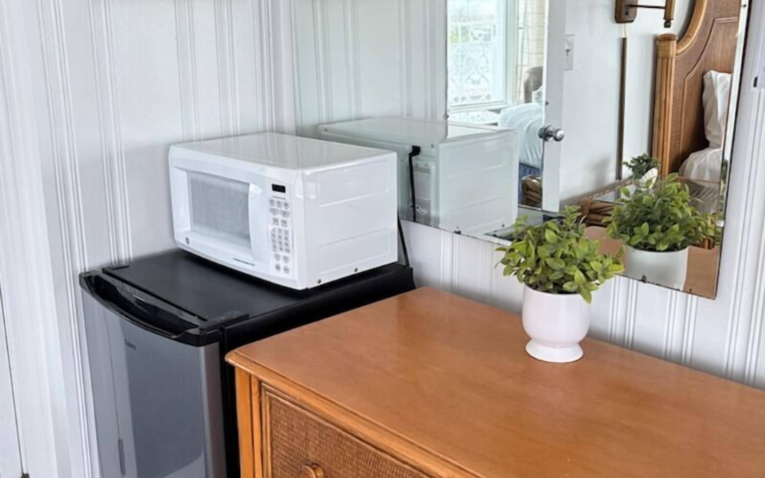 A compact kitchenette with a microwave, a small refrigerator, and a wooden cabinet.