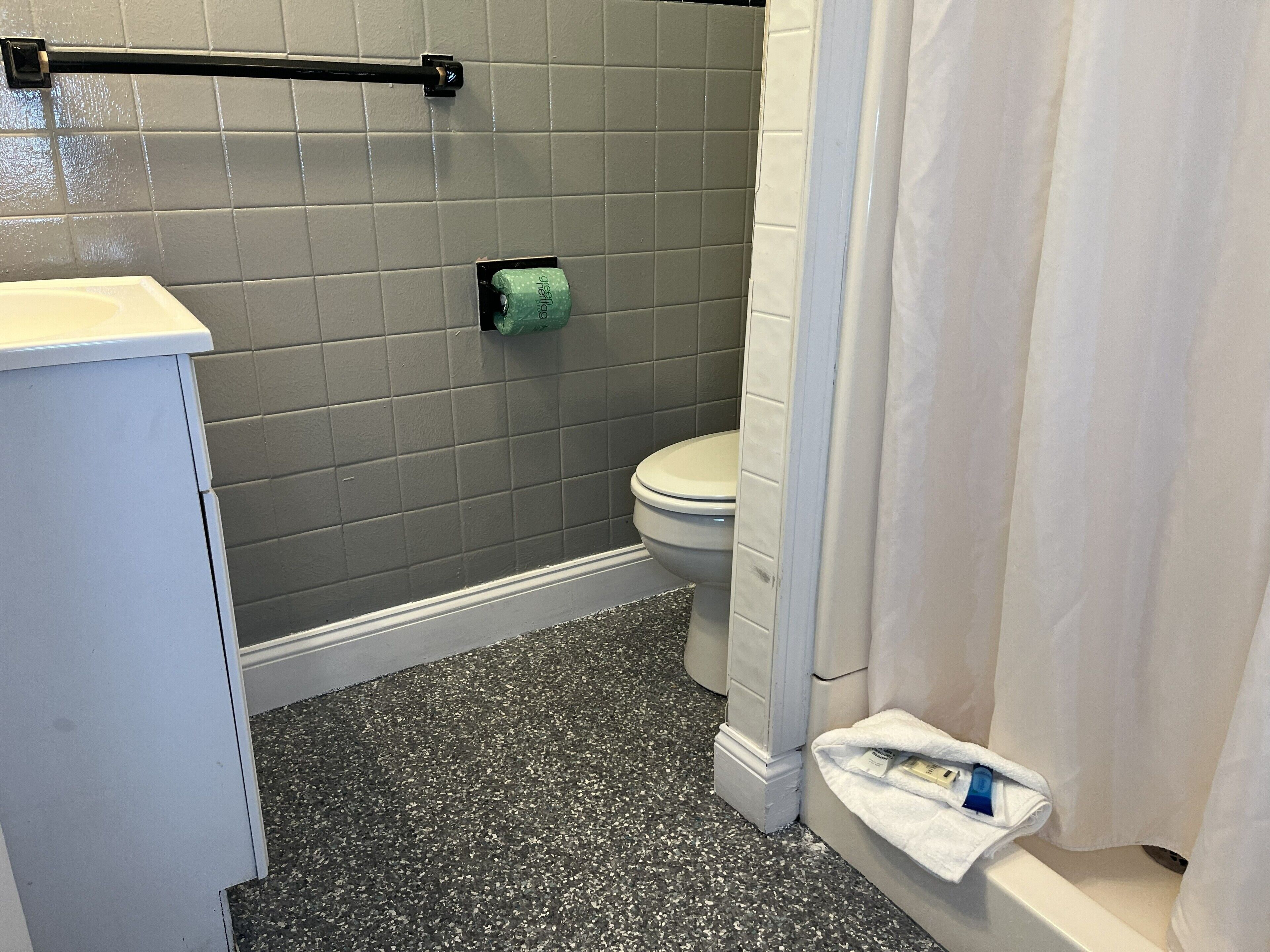 A bathroom with a toilet, a towel rack, and a shower curtain.