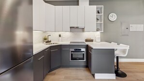 A modern kitchen with grey cabinets, a stainless steel refrigerator, a built-in oven, and a white countertop. - 24 Stay Rittenhouse (Philadelphia)