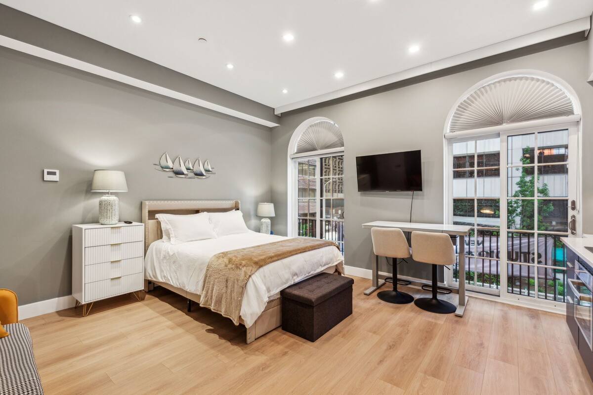 Un dormitorio moderno con cama, mesitas de noche, escritorio y televisor.