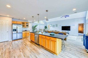 A spacious kitchen with a central island, wooden cabinets, and a large refrigerator.
