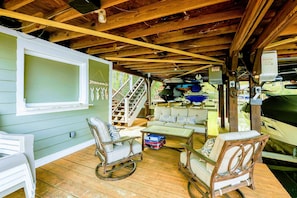 A covered porch with wooden flooring, rocking chairs, a table, and a staircase leading to an upper level.