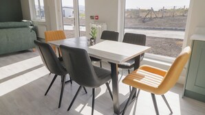 Spiseområde med et bord, stole og udsigt udad.