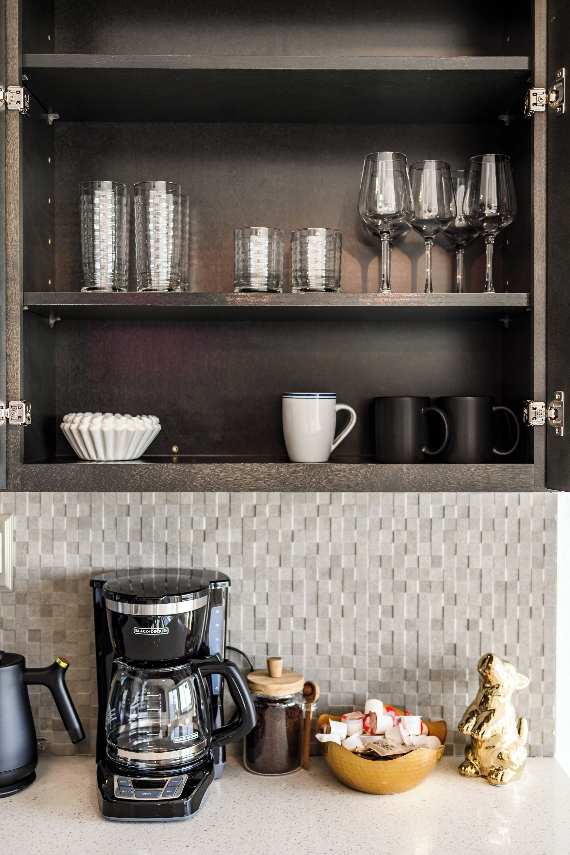 A kitchen with a coffee maker, a bowl of snacks, and a decorative gold figurine.