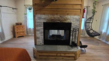 A room with a fireplace, a television mounted on a wooden beam, and a hanging plant.