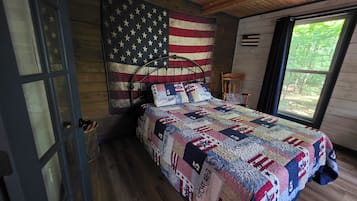 Un dormitorio con cama, una bandera estadounidense, una ventana y techo de madera.