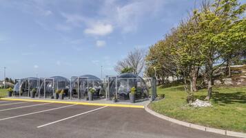 A parking lot with clear, transparent structures housing potted plants.