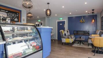 A modern cafe with a glass display case, blue walls, and contemporary furniture.